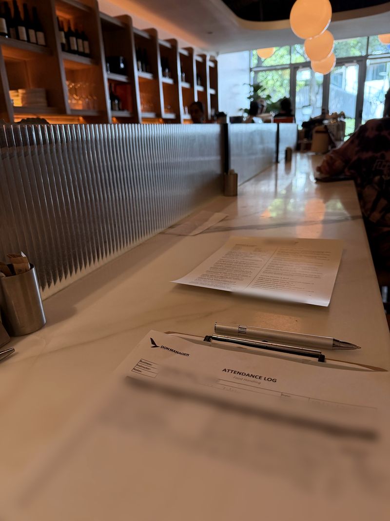 A Don Manager attendance log for a Food Handler class, with a pen, on the bar counter of a restaurant