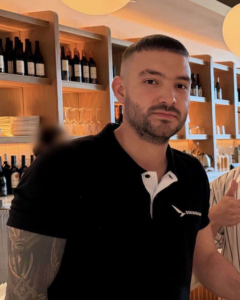 The instructor in a black Don Manager polo, at the bar of a restaurant after an on-site class